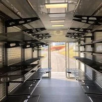 Interior of a trailer with multiple metal shelves and bright lighting.