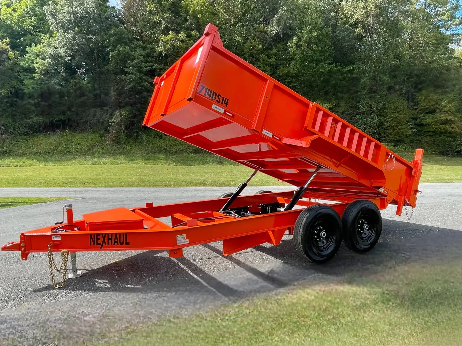 Bright orange Nexhaul dump trailer with raised bed and dual axles parked on a road.